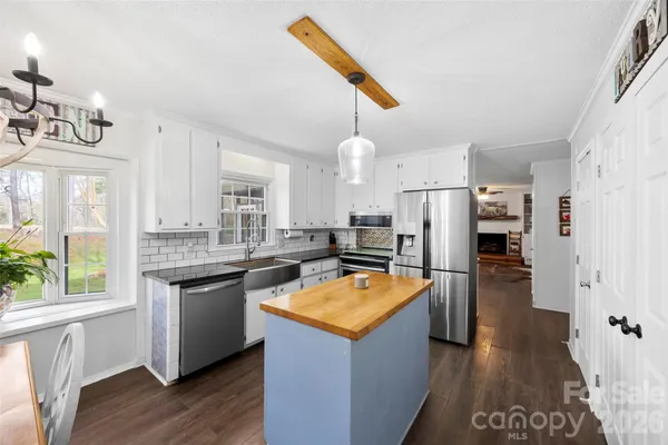 a kitchen with stainless steel appliances granite countertop a refrigerator a sink dishwasher a stove and white countertops with wooden floor