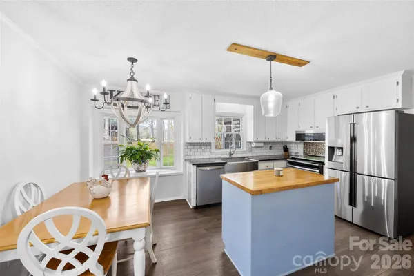 a kitchen with stainless steel appliances granite countertop a sink a stove a refrigerator a dining table and chairs with wooden floor