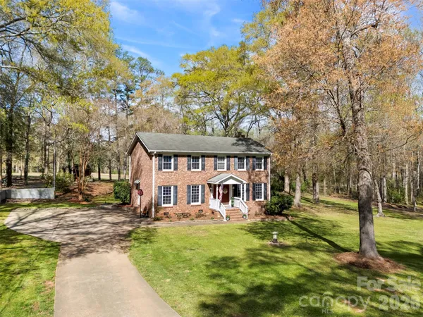 a view of a house with a big yard and large tree