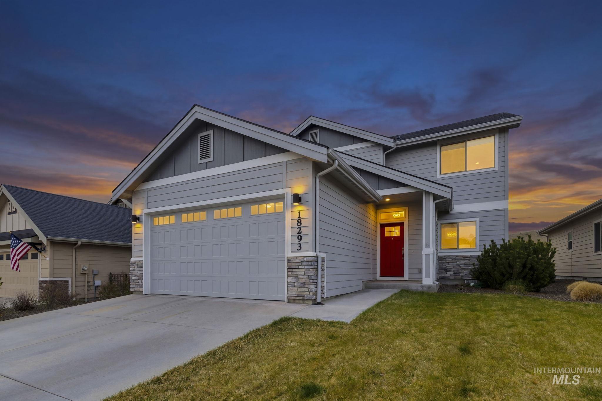 View of front of property featuring stone siding, concrete driveway, a garage, board and batten siding, and a front lawn