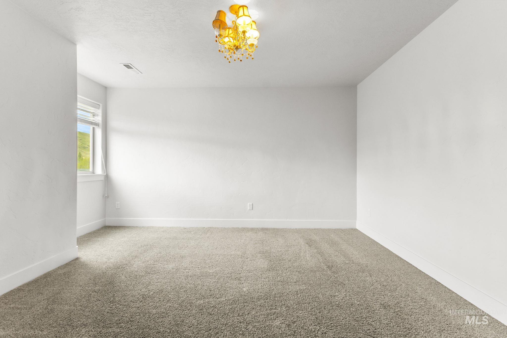 18293 North Streams Edge Way Boise, ID 83714 - Photo 29 of 50 Carpeted spare room with baseboards and a chandelier
