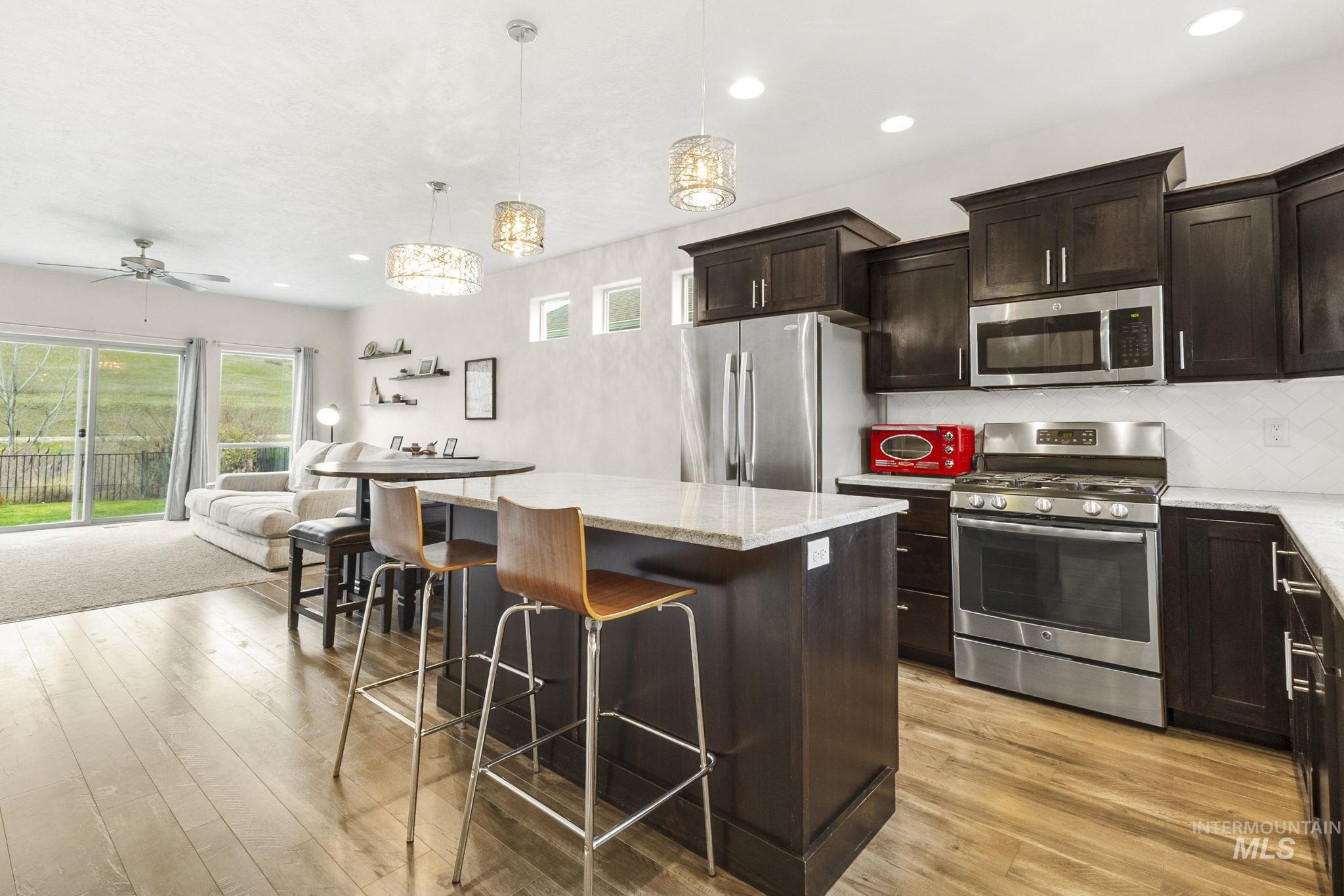18293 North Streams Edge Way Boise, ID 83714 - Photo 49 of 50 Kitchen with stainless steel appliances, a kitchen island, light stone countertops, open floor plan, and dark wood finish cabinets