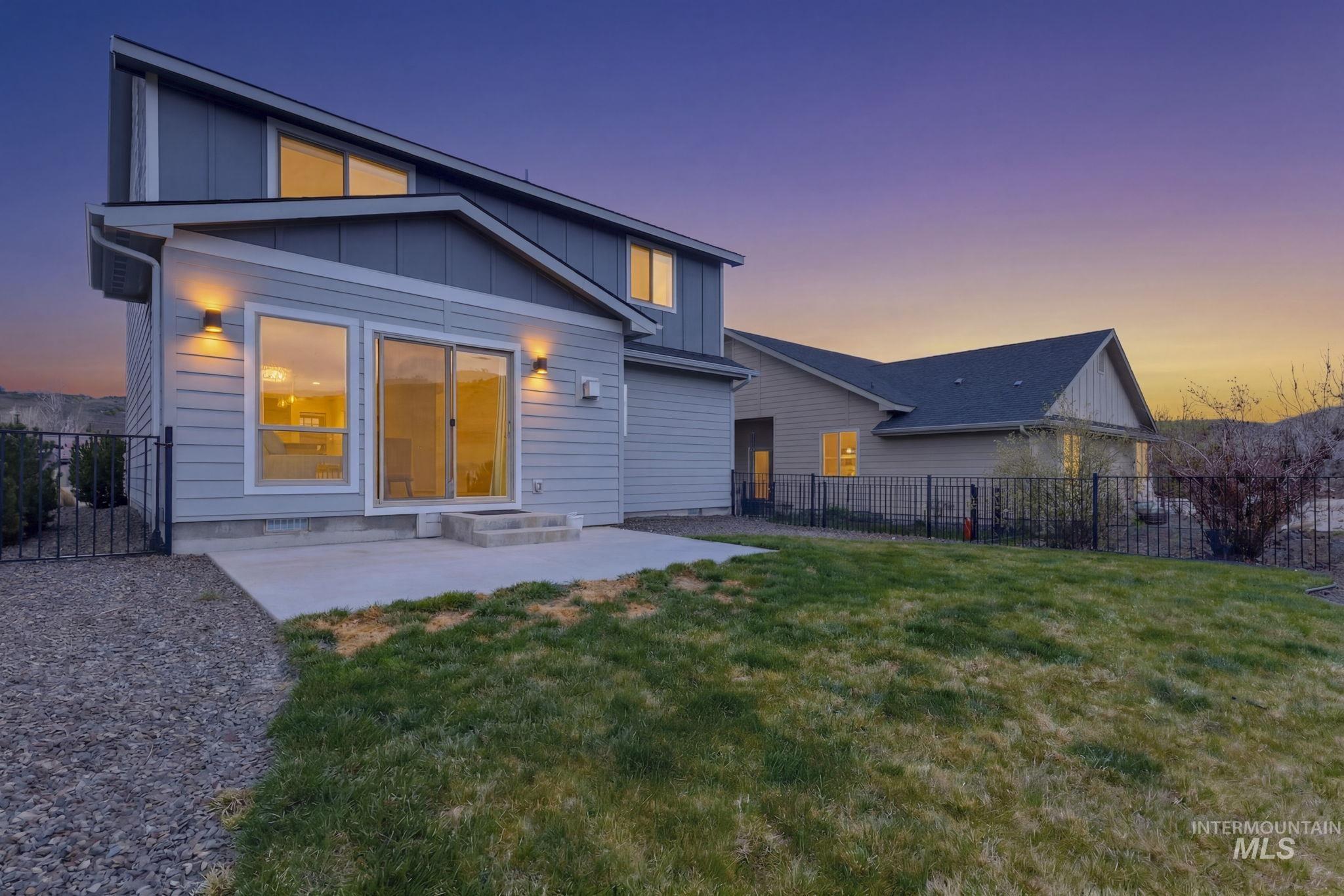18293 North Streams Edge Way Boise, ID 83714 - Photo 39 of 50 Back of property at dusk with board and batten siding, a fenced backyard, a patio area, and entry steps