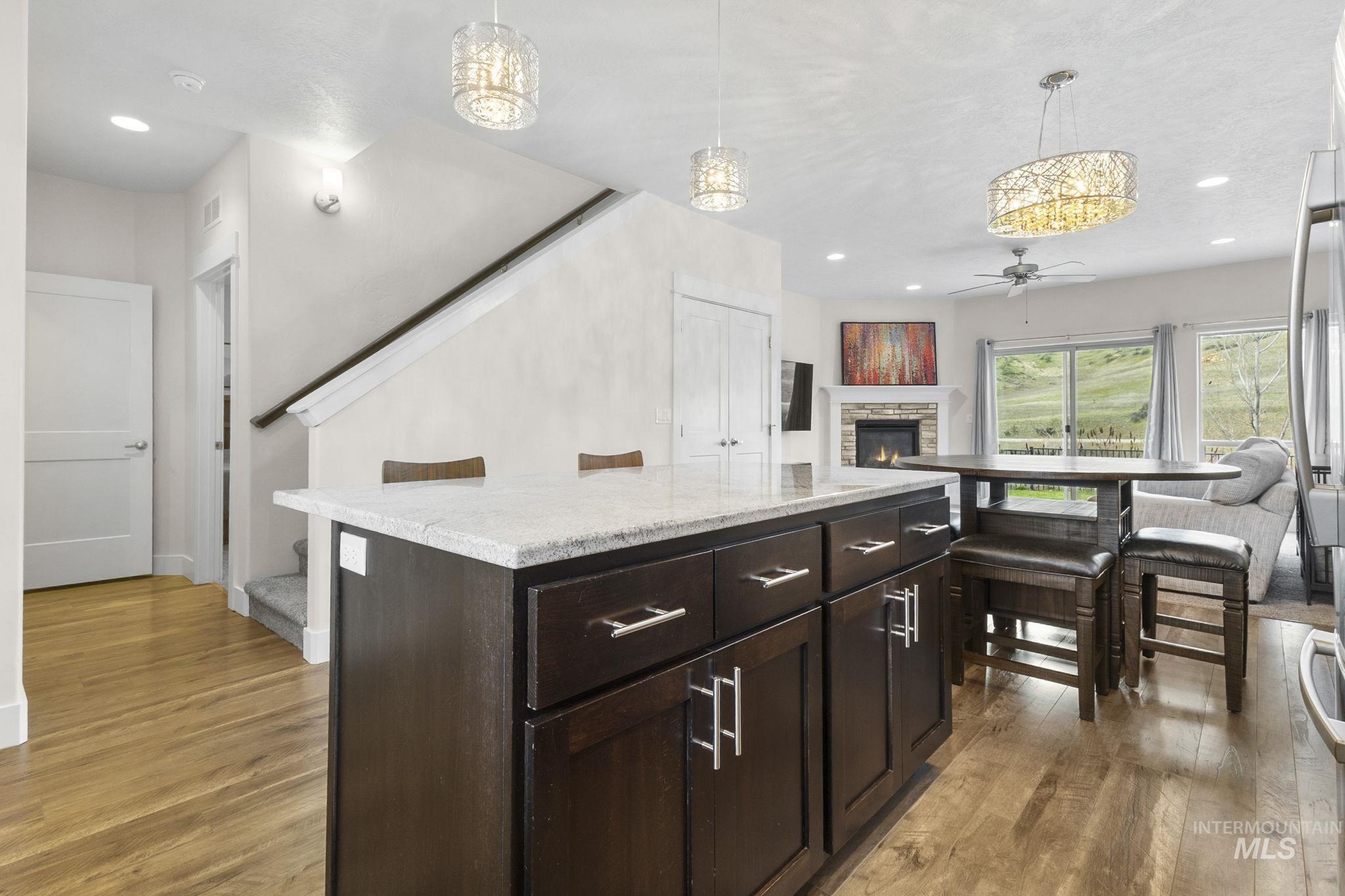 18293 North Streams Edge Way Boise, ID 83714 - Photo 50 of 50 Kitchen with a stone fireplace, dark wood finish cabinetry, pendant lighting, light wood-style flooring, and open floor plan