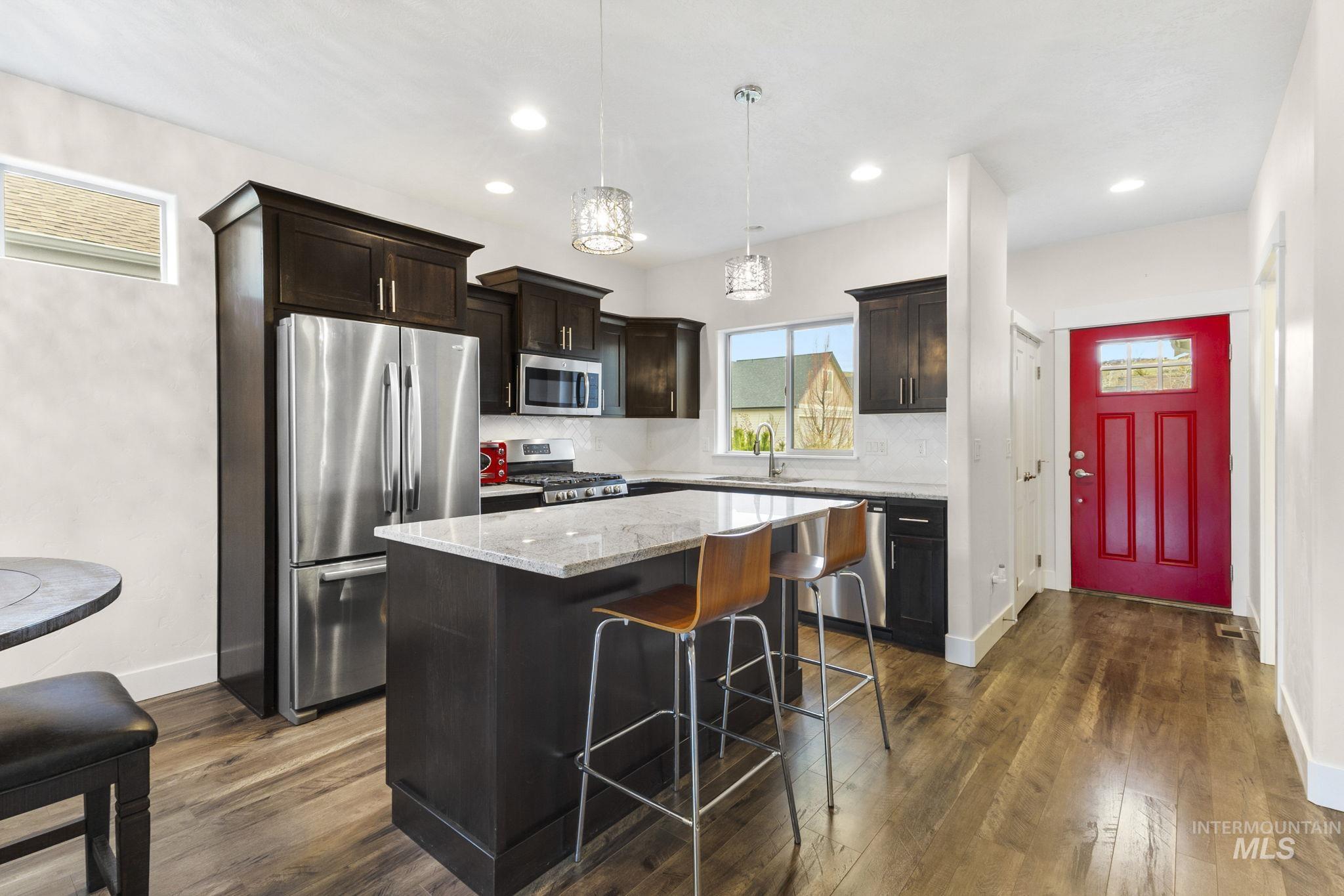 18293 North Streams Edge Way Boise, ID 83714 - Photo 5 of 50 Kitchen featuring stainless steel appliances, light stone counters, a center island, and dark wood finish cabinetry