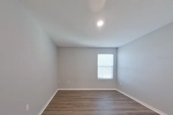 an empty room with wooden floor and window
