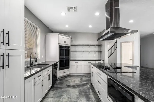 a large kitchen with kitchen island granite countertop a large counter top a sink stainless steel appliances and cabinets