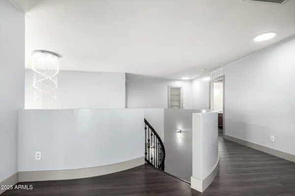 an empty room with wooden floor chandelier fan and windows
