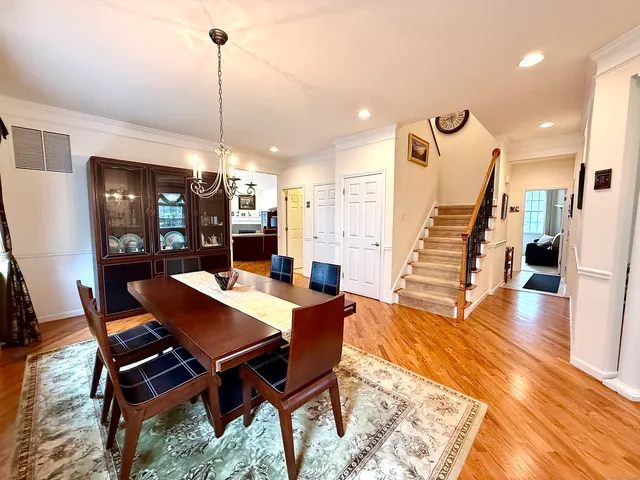 a view of a dining room and livingroom with furniture wooden floor a rug a chandelier