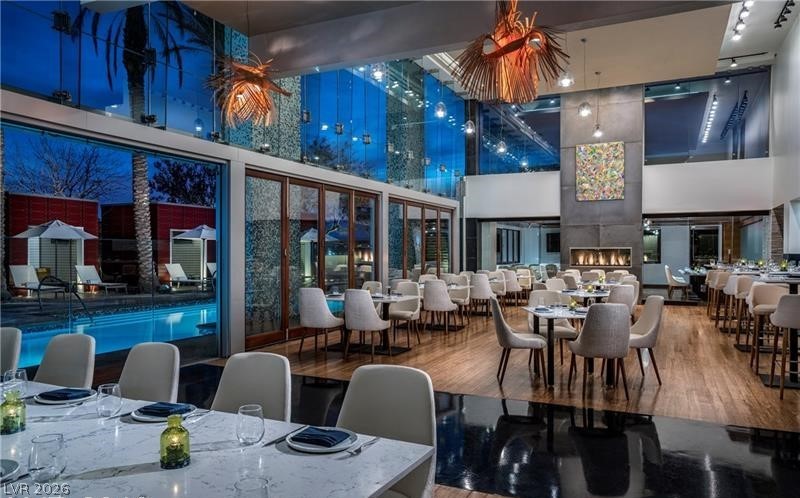 4381 West Flamingo Road, Unit 15310 Las Vegas, NV 89103 - Photo 26 of 52 Dining area featuring rail lighting, wood finished floors, and a towering ceiling