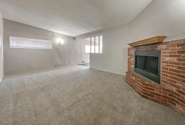 a view of an empty room with wooden floor and a fireplace