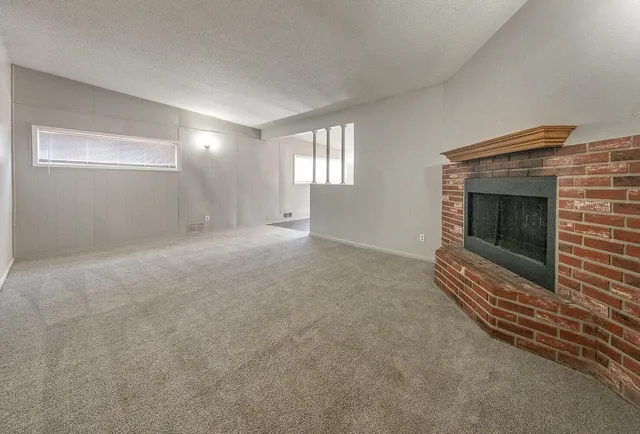 a view of an empty room with wooden floor and a fireplace