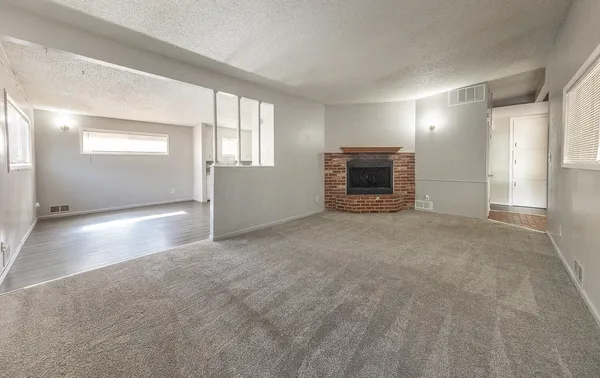 a view of an empty room with a fireplace and a window