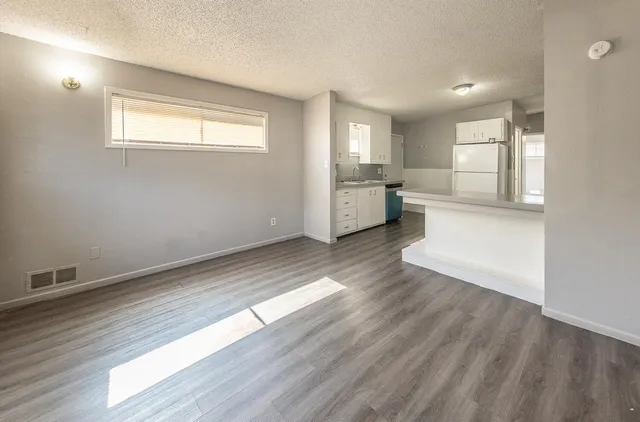 a view of an empty room with a window and wooden floor