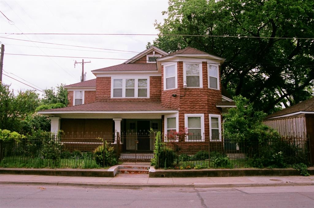 Victorian house with covered porch, a shingled roof, and a fenced front yard