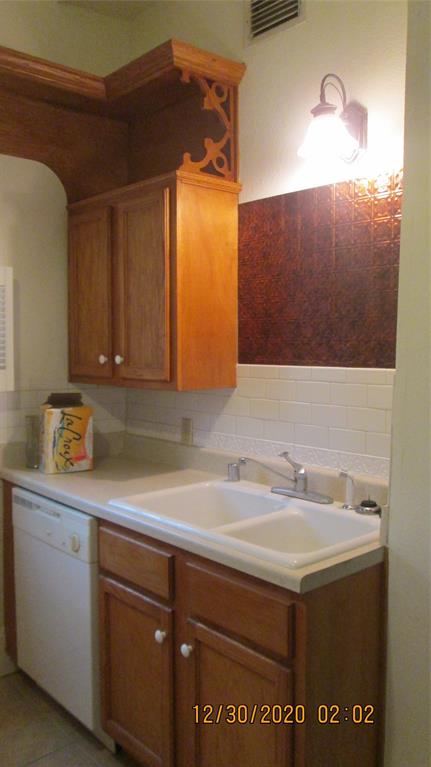 203 North Colson Street, Unit 4 Dallas, TX 75246 - Photo 13 of 15 Kitchen with dishwashing machine, brown cabinets, tasteful backsplash, and light countertops
