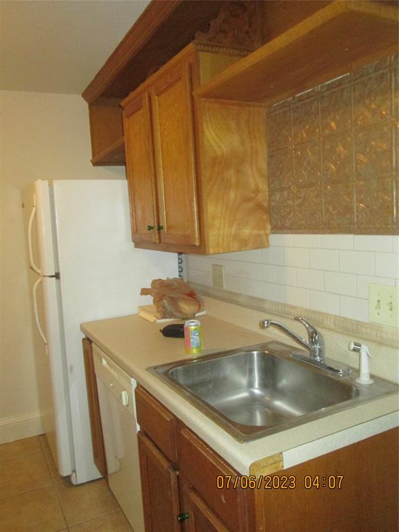 203 North Colson Street, Unit 4 Dallas, TX 75246 - Photo 5 of 15 Kitchen featuring dishwashing machine, a sink, brown cabinets, light tile patterned flooring, and light countertops