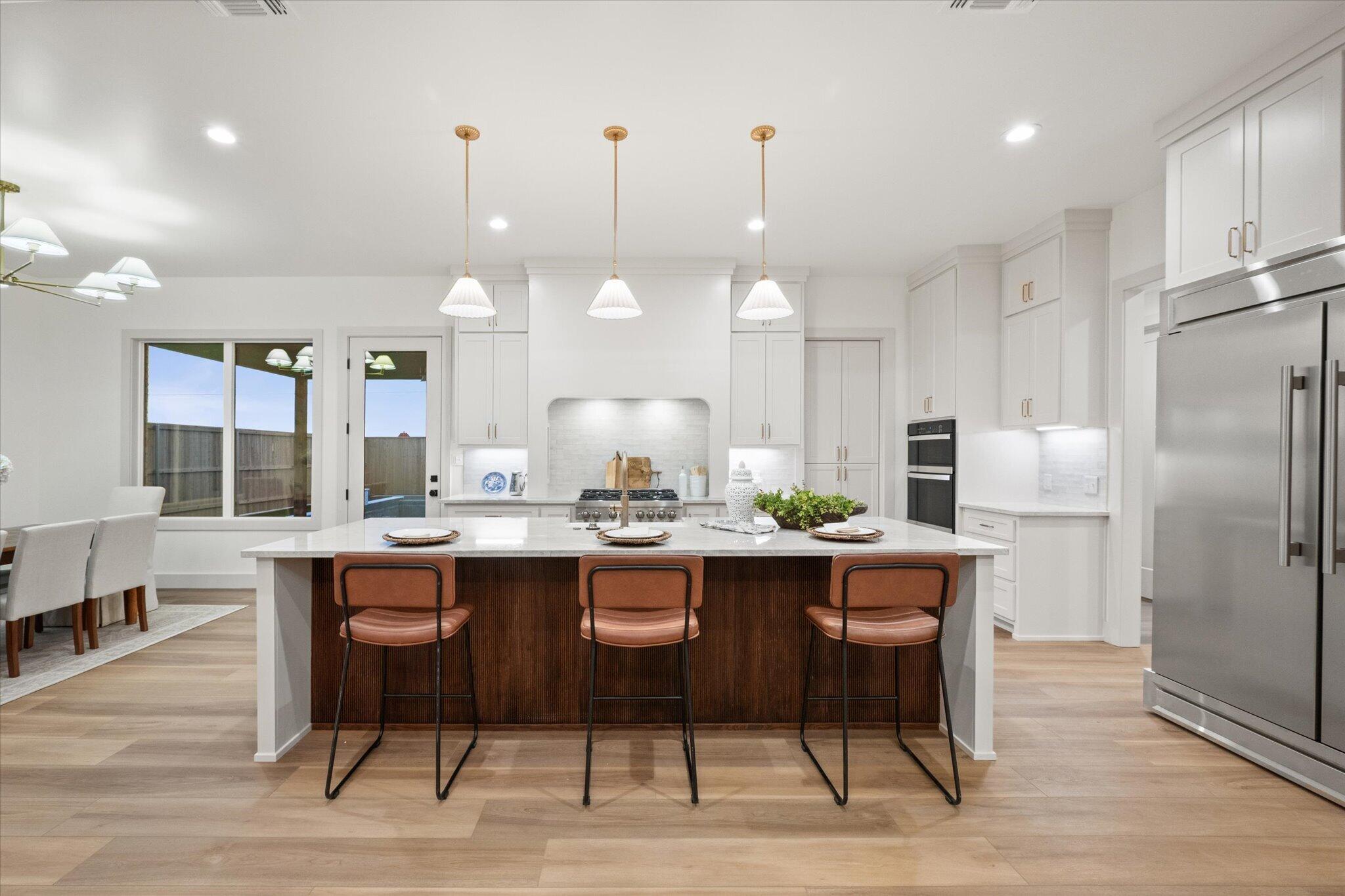 4622 138th Place Lubbock, TX 79424 - Photo 10 of 48 a kitchen with stainless steel appliances a dining table chairs stove refrigerator and cabinets