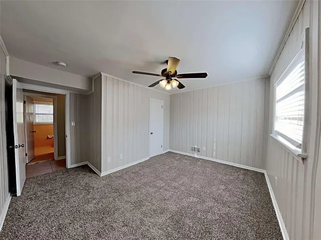 a view of an empty room with wooden floor and a ceiling fan