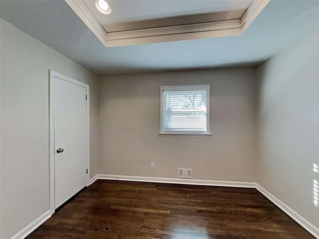 a view of an empty room with wooden floor and closet