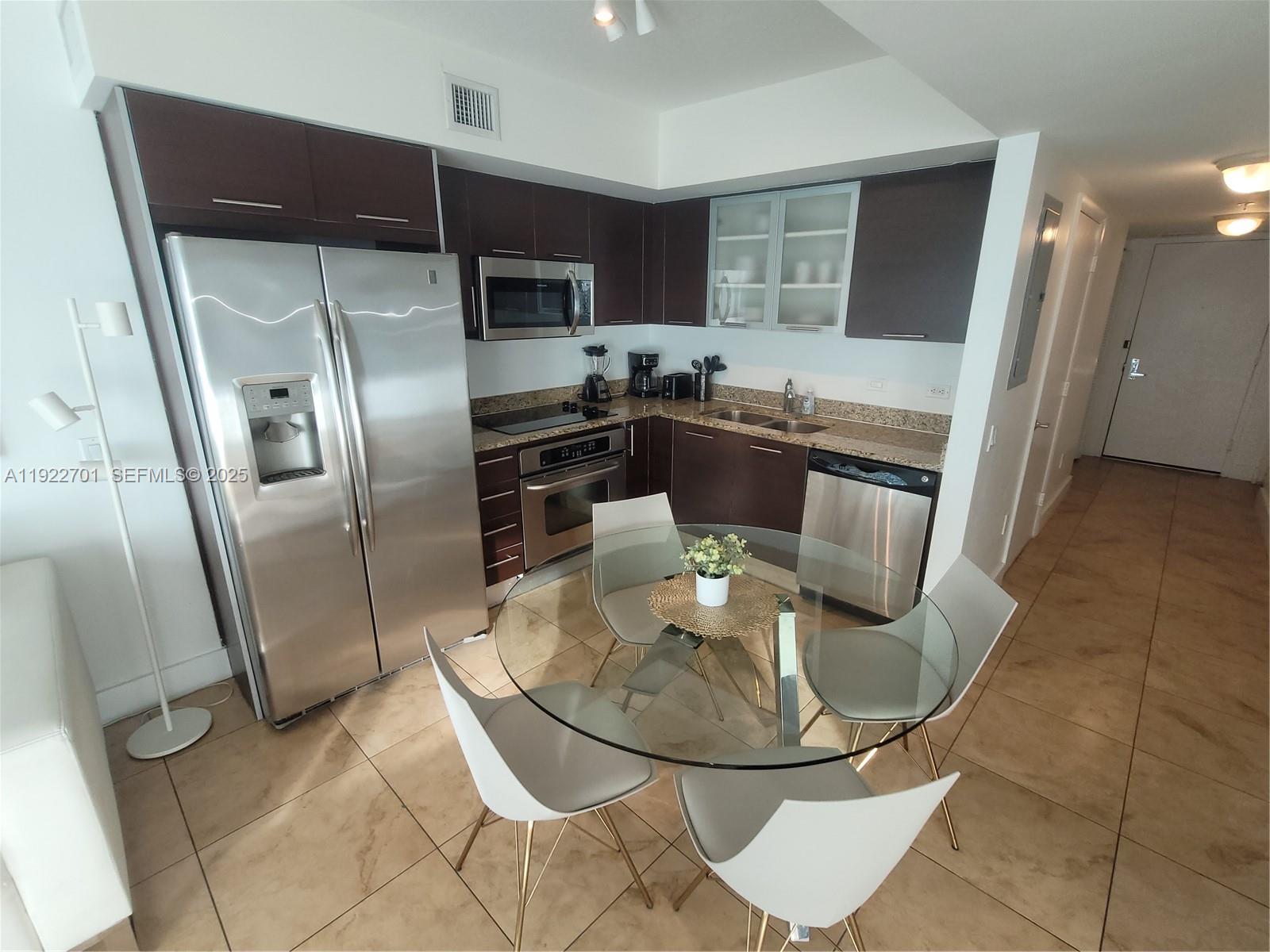 41 Southeast 5th Street, Unit 710 Miami, FL 33131 - Photo 7 of 14 a kitchen with stainless steel appliances granite countertop a refrigerator a stove a microwave oven a sink with island and chairs