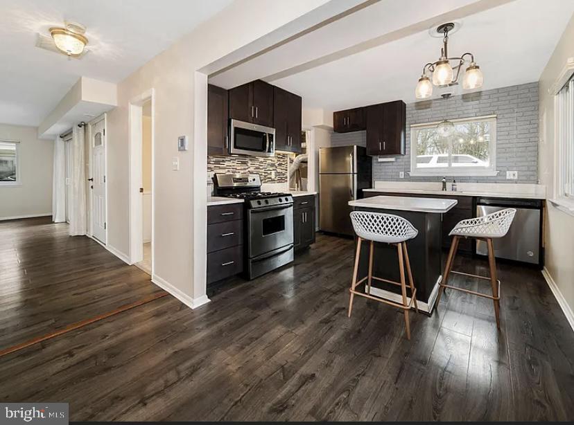 9481 Farewell Road Columbia, MD 21045 - Photo 9 of 18 a kitchen with stainless steel appliances a dining table chairs and wooden floor