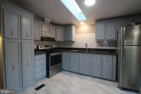 a kitchen with granite countertop a refrigerator sink and cabinets