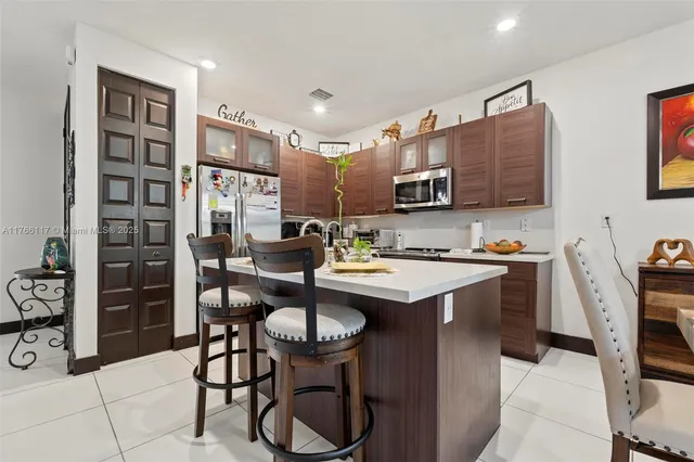 a kitchen with stainless steel appliances kitchen island granite countertop a sink and a refrigerator
