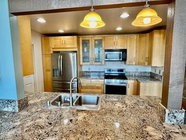 a kitchen with granite countertop a stove and a refrigerator