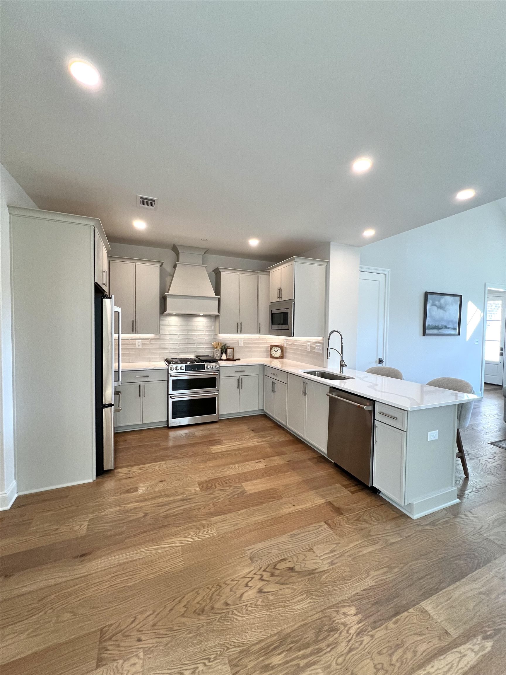 110 Rambling Rex Trail Collierville, TN 38017 - Photo 11 of 36 Kitchen featuring premium range hood, a peninsula, stainless steel appliances, tasteful backsplash, and a breakfast bar