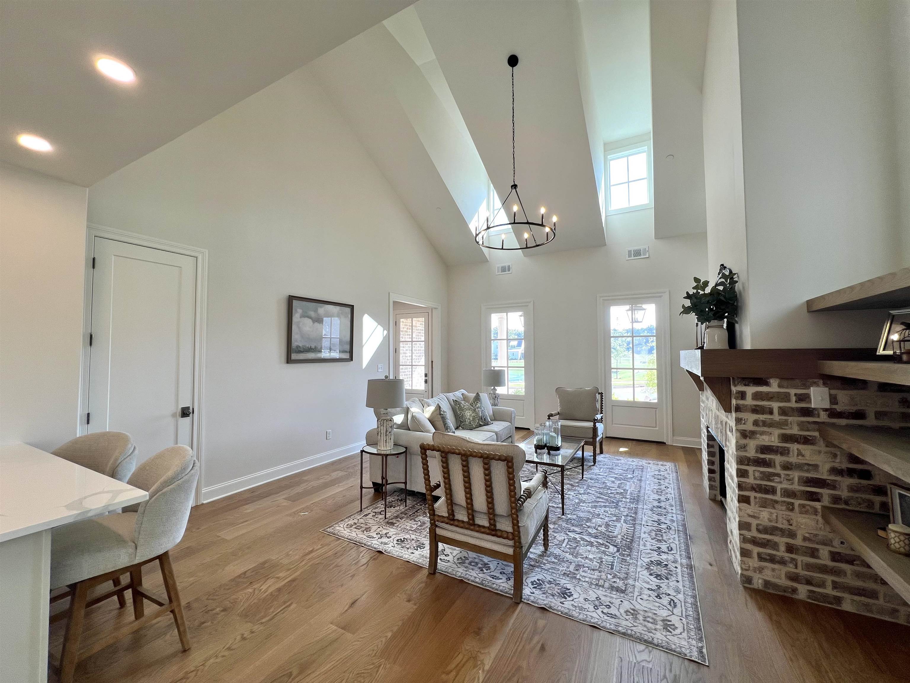 110 Rambling Rex Trail Collierville, TN 38017 - Photo 6 of 37 Living room featuring high vaulted ceiling, a chandelier, light wood-style flooring, and a brick fireplace