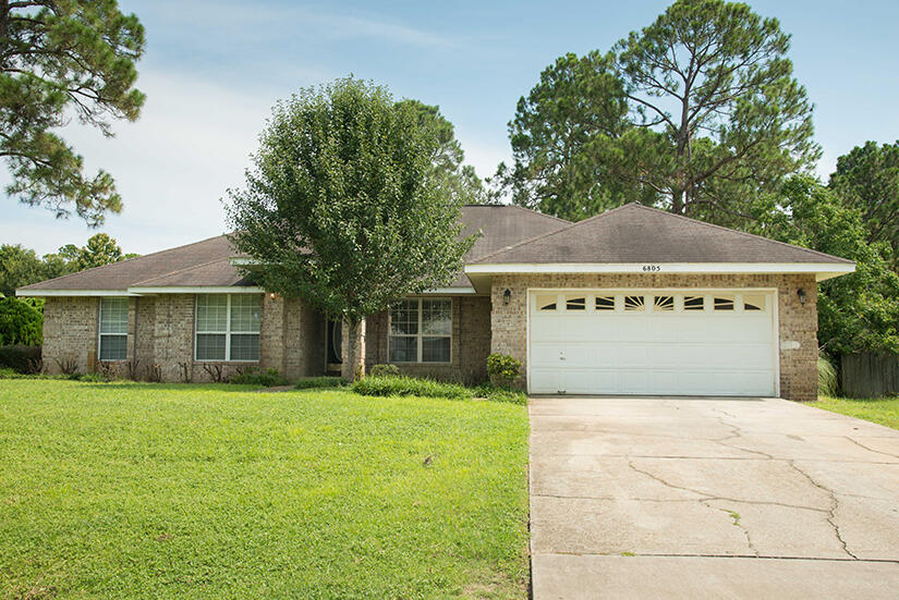 a view of a house with a yard and large trees