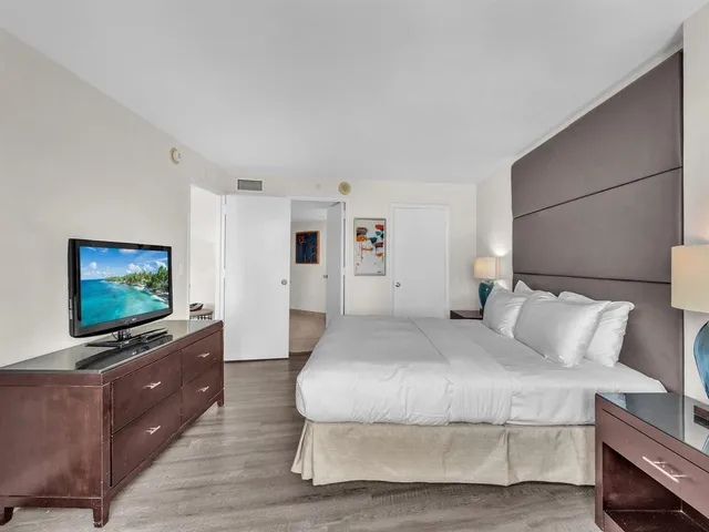 a bedroom with a flat screen tv on dresser and a table