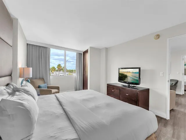 a bedroom with a bed and a flat tv screen on the dresser
