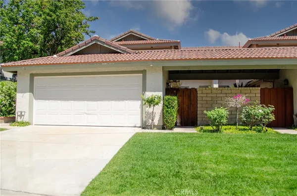 a front view of a house with a yard and potted plants