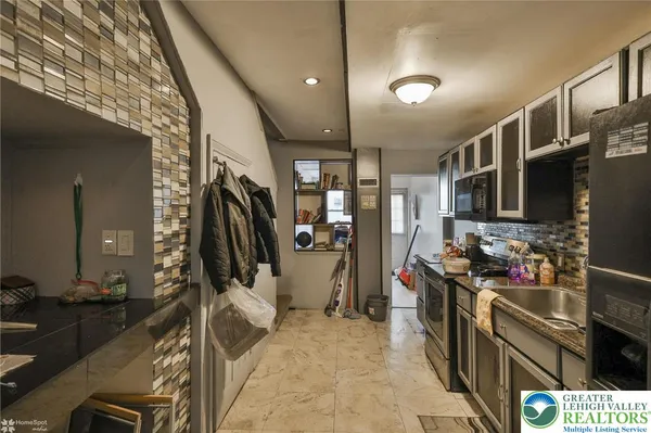 a kitchen with stainless steel appliances kitchen island granite countertop a stove a refrigerator a sink a dining table and chairs with wooden floor