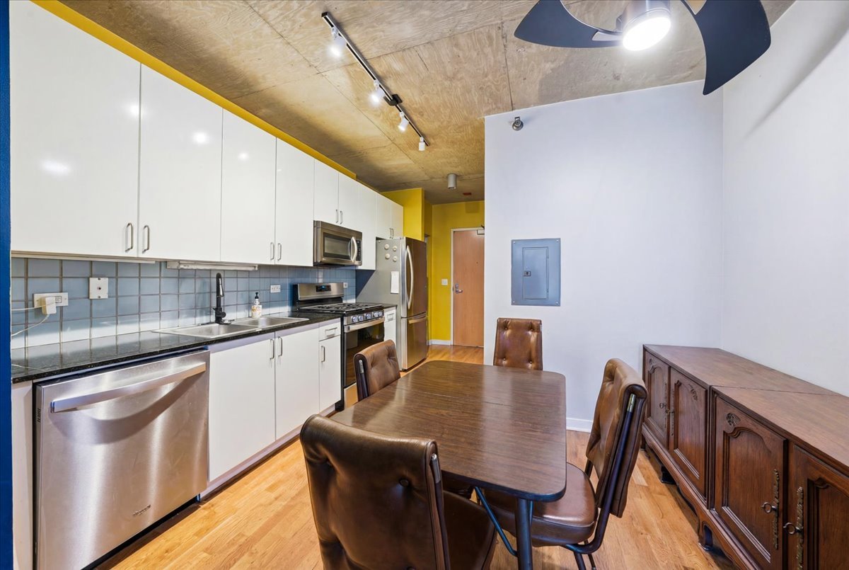611 South Wells Street, Unit 1110 Chicago, IL 60607 - Photo 7 of 19 a kitchen with stainless steel appliances granite countertop a stove a refrigerator a kitchen island a dining table and chairs with wooden floor