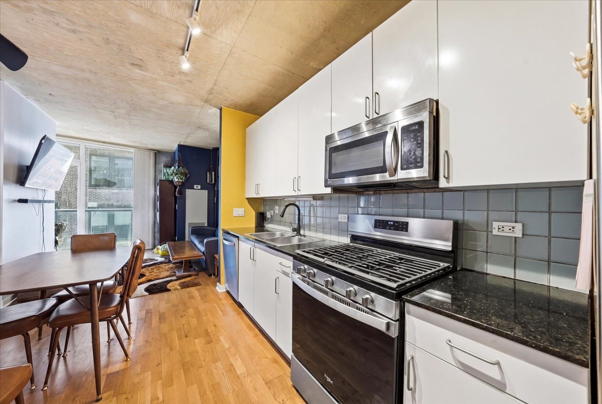 611 South Wells Street, Unit 1110 Chicago, IL 60607 - Photo 8 of 19 a kitchen with stainless steel appliances a stove a sink cabinets and a wooden floor