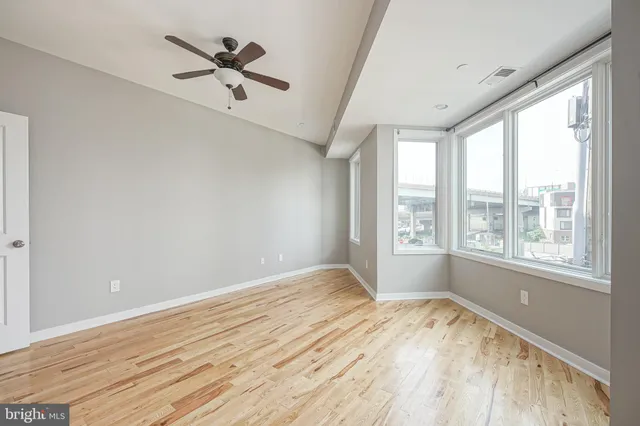 a view of empty room with wooden floor and fan