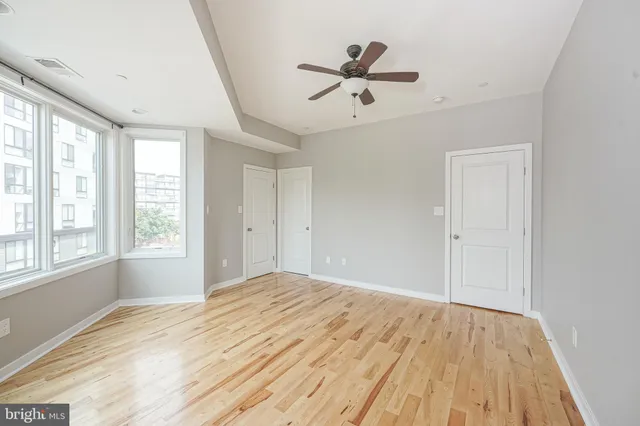 a view of empty room with wooden floor and fan