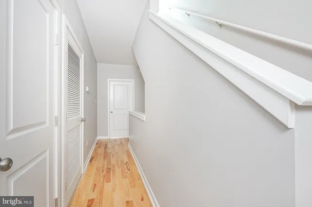 a view of a hallway with wooden floor and a bathroom