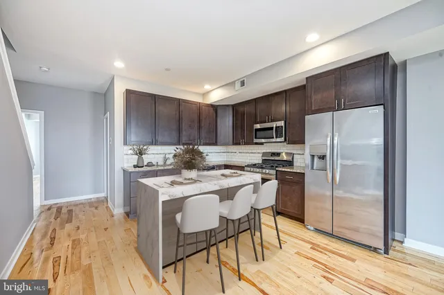 a kitchen with a refrigerator a stove top oven a sink and dishwasher with wooden floor