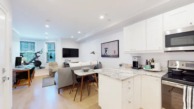 a living room with furniture a flat screen tv and kitchen view