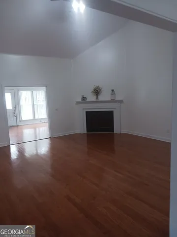 a view of an empty room and wooden floor and a window