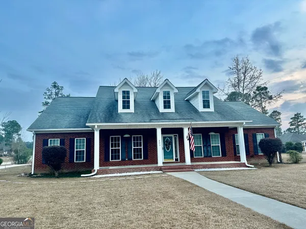 a view of a brick house with large windows and a big yard