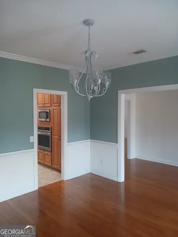 a view of a hallway with wooden floor and chandelier