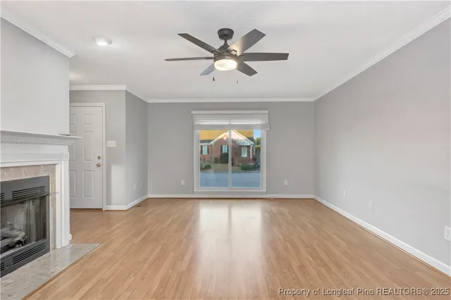 an empty room with wooden floor a ceiling fan and a fireplace