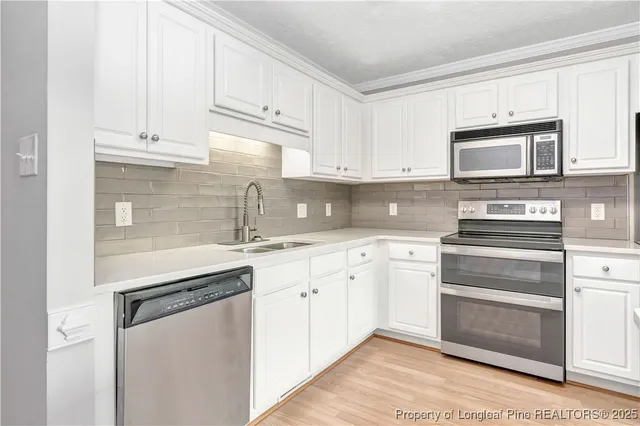 a kitchen with granite countertop white cabinets and stainless steel appliances