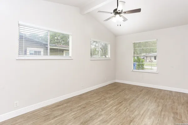 a view of an empty room with wooden floor and a window
