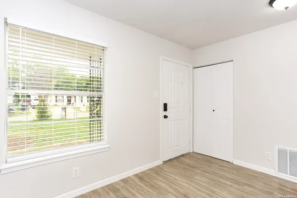 a view of an empty room with wooden floor and a window